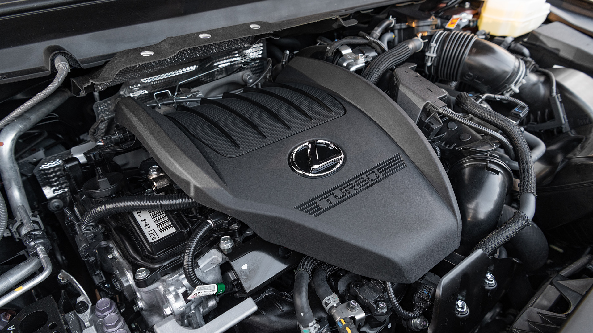 The engine bay of the RX, with the engine cover marked with the lexus logo and the word turbo.